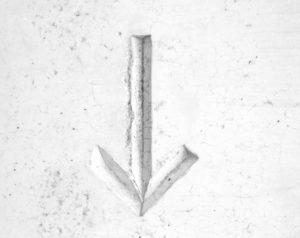 arrow etched in white marble pointing down