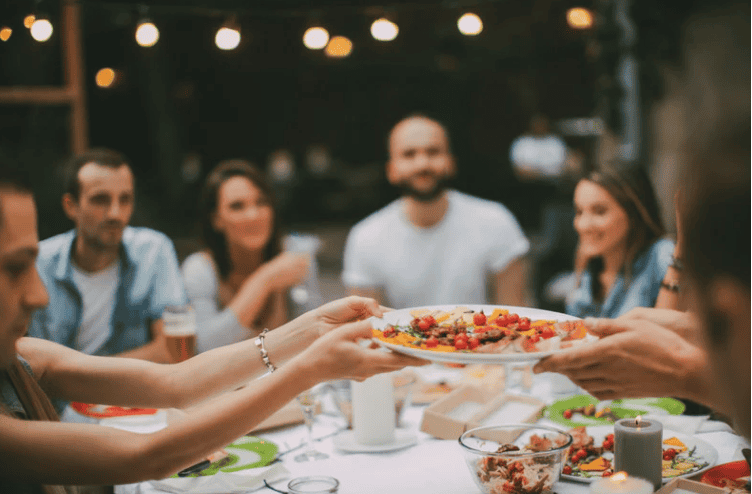 Groups of friends eating and passing a plate 