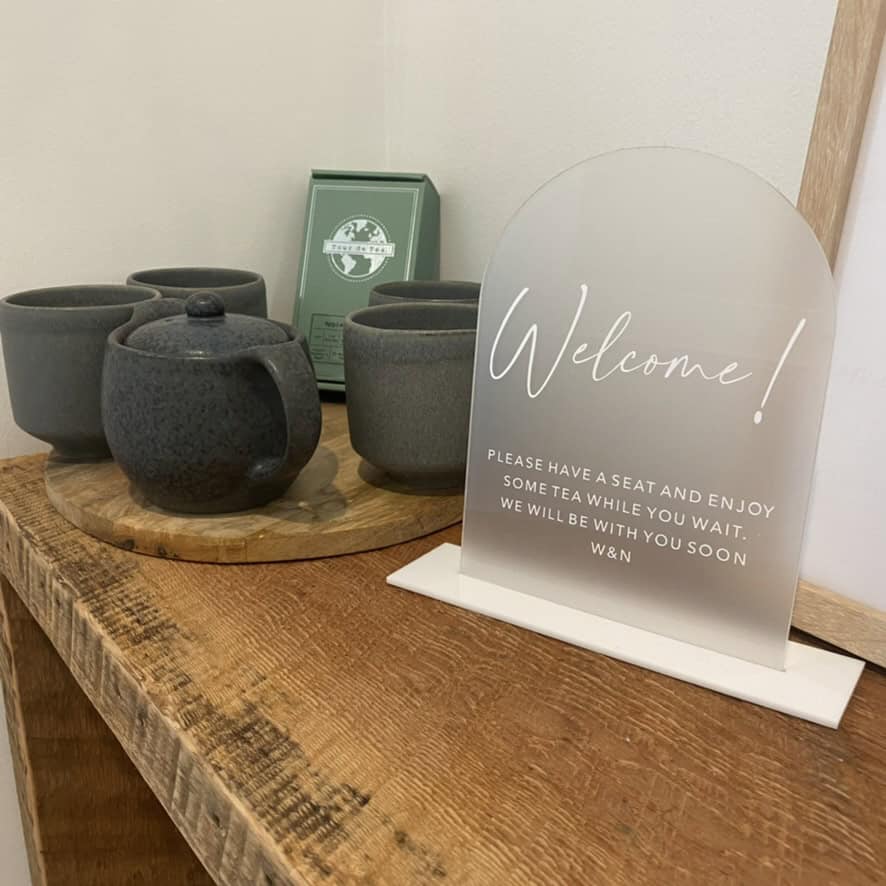 Welcome sign for Dietitian clinic on wooden table next to tea pot and cups